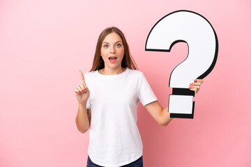 Young Lithuanian woman isolated on pink background holding a question mark icon