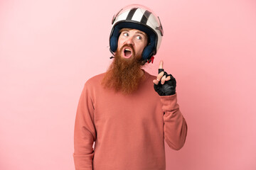 Young reddish caucasian man with a motorcycle helmet isolated on pink background thinking an idea...