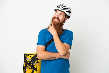 Young reddish caucasian man with thermal backpack isolate don white background looking up while smiling