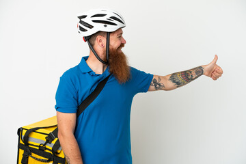Young reddish caucasian man with thermal backpack isolate don white background giving a thumbs up gesture