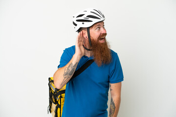 Young reddish caucasian man with thermal backpack isolate don white background listening to something by putting hand on the ear