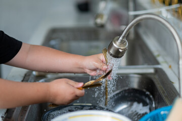 Close up hands washing spoon and fork