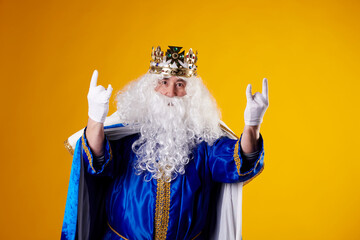 A man dressed as a king making a rocker gesture on a yellow background