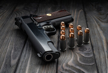 Pistol and cartridges for it on a wooden backg. A short-barreled weapon for self-defense.