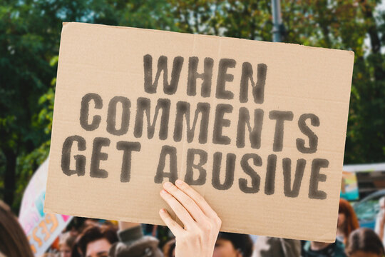 The phrase " When comments get abusive " on a banner in men's hand with blurred background. Communication. Relationship. Dangerous. Behaviour. Friendship. Emotional. Negotiation. Psychology. Society