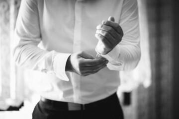 Groom buttoning his shirt and preparing for the wedding ceremony