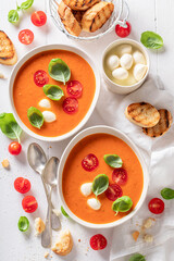 Red creamy tomato soup with mozzarella cheese and crostini.