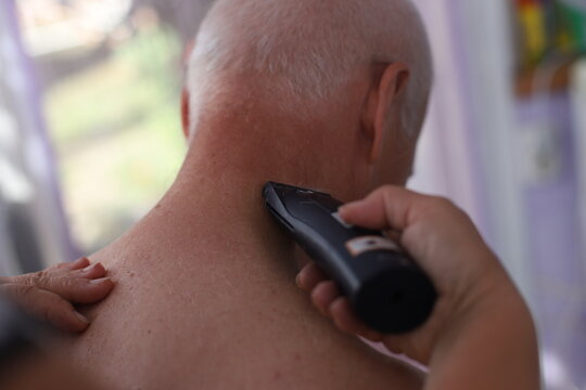 Mature Handsome Man With Short Silver Hair At Home. Elderly Man Getting Haircutting With Electric Clipper