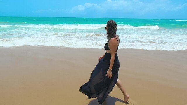 Beautiful woman walking on the sand of a beautiful beach of the northeast brazilian coast. Cupe beach at Ipojuca PE, Brazil.