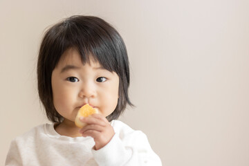 小さいパンを自分で食べる赤ちゃん（1歳5か月
、女の子、日本人）