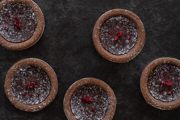 Obraz na płótnie Canvas Batch of Delicious Chocolate Tarts from Above on Dark Background