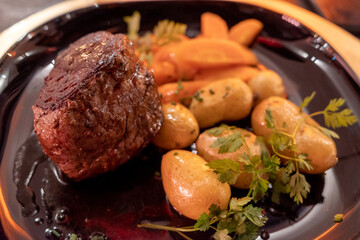 Top and selective focus view at beef steak with potato and carrot.