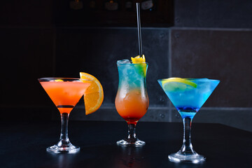 Delicious and refreshing cocktails in blue and orange color gradient at the bar table