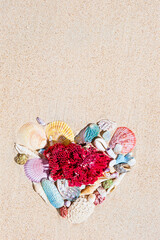 Red corals and colourful sea shells on pure white fine beach sand on shape of heart. Top view, flat...
