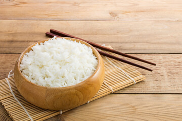 White rice or jasmine rice in a wooden bowl with chopsticks placed on the wooden floor