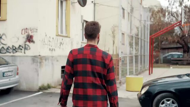 A young Bosnian man in a red checkered shirt walking on the str