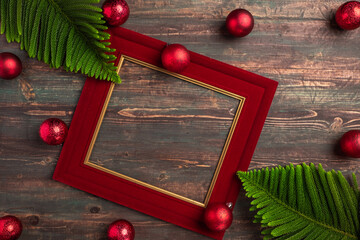Christmas red picture frame with pine leaf and bauble decor on wood table