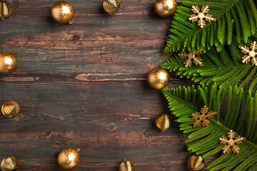 Christmas pine leaf with golden bauble decoration on wooden table