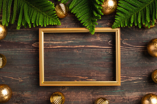 Christmas golden picture frame with pine leaf and bauble decor on wood table