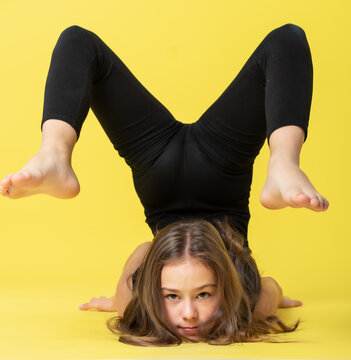 girl gymnast studio. little gymnast performs an exercise on the floor. The concept of sports, gymnastics, fitness. Isolated on a colored yellow background.