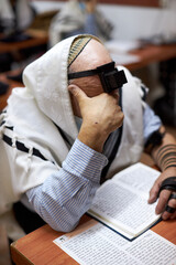 religious Jew with tefillin on his forehead and a tallit on his head praying