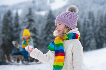 Little girl and boy enjoying a day out playing in the winter forest. Children siblings having fun in beautiful winter park. Happy childhood.