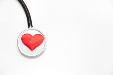 Selective focus on small kid and baby red heart on stethoscope on white background with place for text, top view: cardiologist's day, international Day of Medicine, blood donor