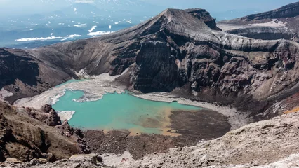 Foto op Canvas There is a turquoise acid lake in the crater at the top of the volcano. There is snow on the banks, deposits of sulfur. The high steep banks are devoid of vegetation. The texture of the soil.  © Вера 
