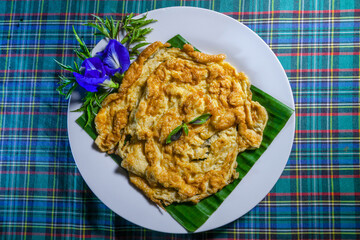 Hot omelette served on fresh banana leaves garnished with orchids and basil leaves.
