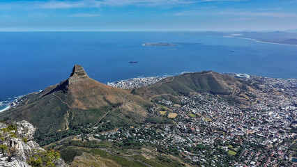 The panorama of Cape Town opens from the top of Table Mountain. City buildings, Signal Hill, Lion's Head Rock are visible. In the distance - the blue Atlantic Ocean, azure sky. South Africa