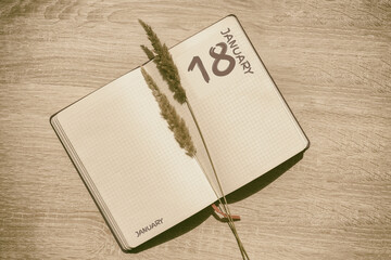 january 18. 18th day of month, calendar date.Blank pages of notebook are beige, with dried...