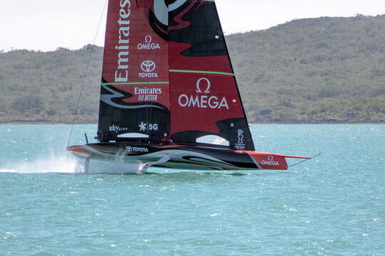 View of Team New Zealand Emirates hydrofoil sailboat making practice planing runs along Rangitoto Island