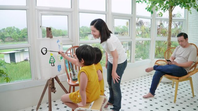 Children drawing and painting at home in an Asian happy family performing activities together.
