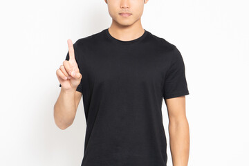 白い背景の前に立って、手で数字の1を表す黒いTシャツを着ている男性