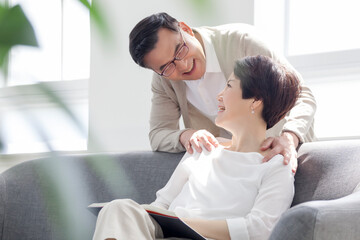 A middle-aged couple relaxing while sitting on the sofa in the living room at home