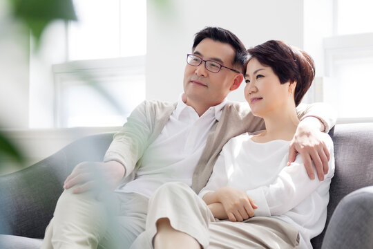 A middle-aged couple relaxing while sitting on the sofa in the living room at home