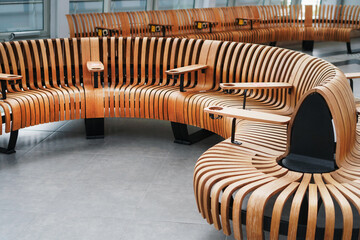 Modern designer curved bench made of natural wood in the airport terminal. - obrazy, fototapety, plakaty