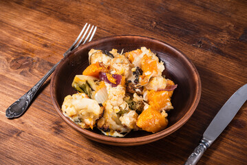 Portion of vegetables with pumpkin baked with cheese in a plate on the table