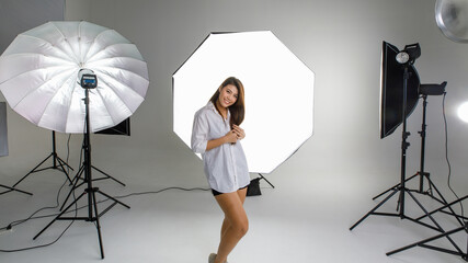 Asian young happy cheerful female model in plaid dress standing smiling look at camera posing in...