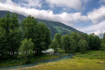 Winding mountain river on the background of peaks and beautiful clouds