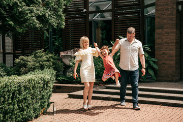  Family with little girl having fun at hotel on vacation. Full family. Happy relationship. Right way of life. Role model. Rest at hotel. Travel and tourism. City park.