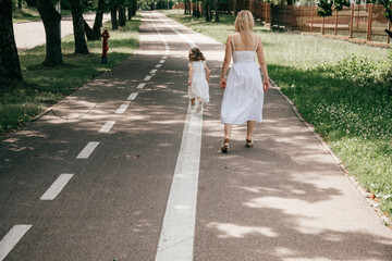 Mom and daughter walk around city square on summer day. Happy relationship. Wonderful childhood....