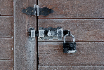 the frozen lock in the cold hangs on the latch on the wooden doors
