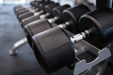 Obraz na płótnie Canvas Rack with many dumbbells at gym, close-up