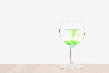 green food coloring is spread in water in a wine glass.