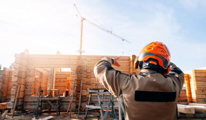 Construction site of wooden cottages houses from log, foreman worker in helmet controls building process, banner