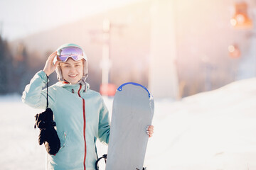 Portrait smile Young woman snowboarder stands with snowboard sunlight background winter ski lift...