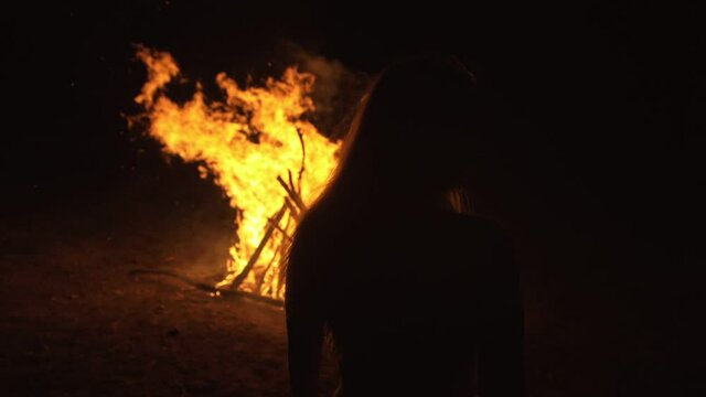 Silhouette of mystic woman in black background of fire fly flame, spark, of contour outline. Outdoor slow motion. Caucasian.
