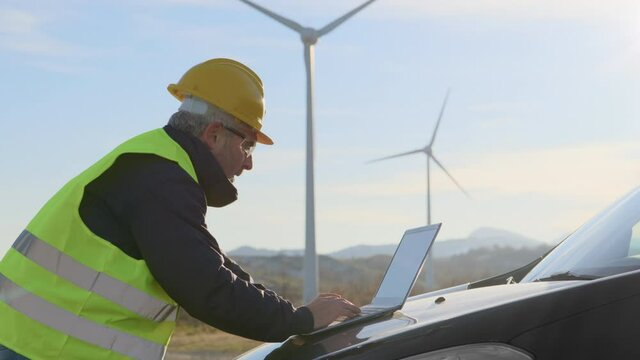 technician engineer working at wind turbine plant using laptop computer,worker or operator checks wind turbine farm does maintenance to power generator station 