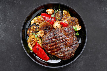 Meat steak with grilled vegetables on a dark plate